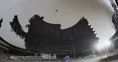 Interiér poloprázdného stadionu za šera s jedním vznášejícím se ptákem